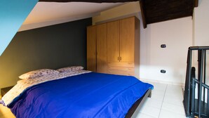 Un dormitorio con cama, armario de madera y una escalera.