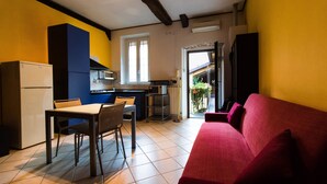 Un espacio habitable compacto con kitchenette, zona de comedor y sofá rojo.