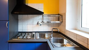 Una cocina moderna con estufa a gas, pileta de acero inoxidable y campana extractora negra.