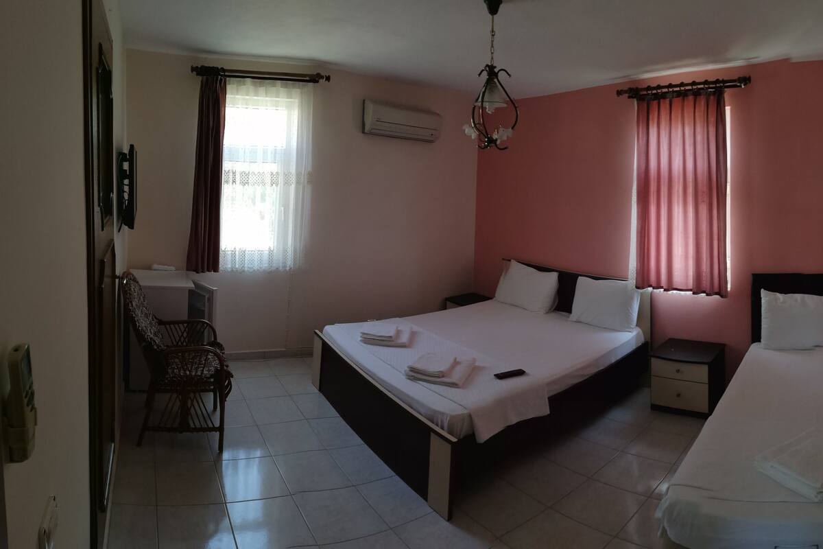 A bedroom with two beds, a desk, and a chair.