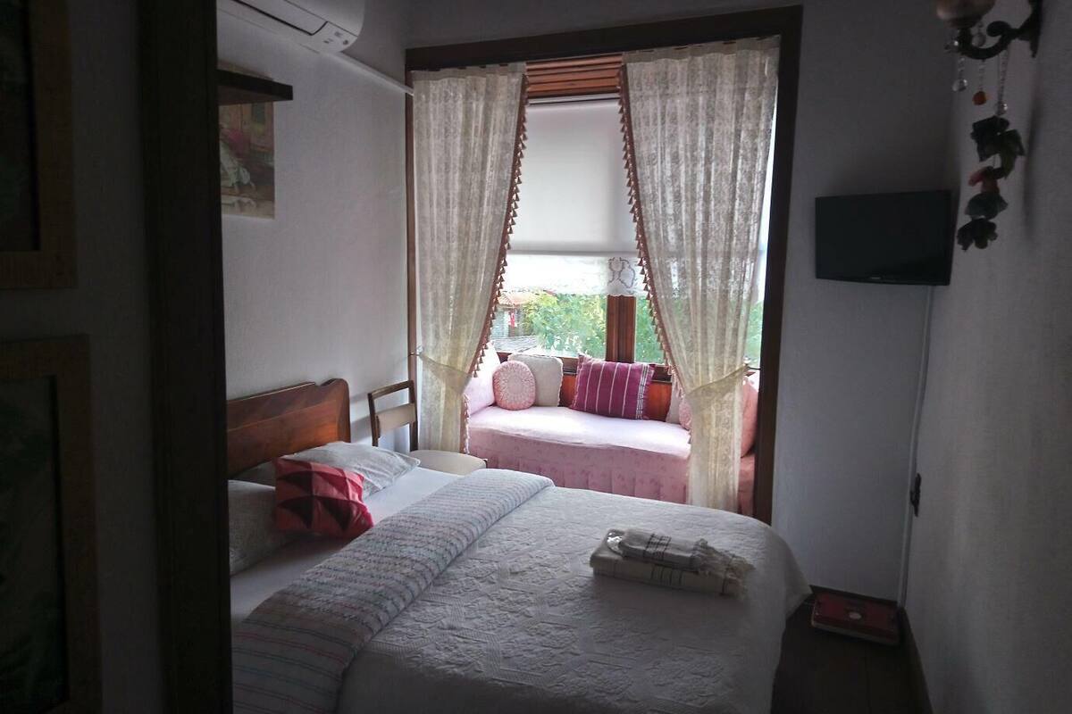 Un dormitorio con cama, una silla y un ventanal con cortinas.