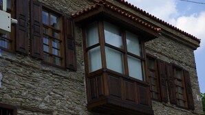 Ein Gebäude aus Stein mit hölzernen Fensterläden und einem Ziegeldach.