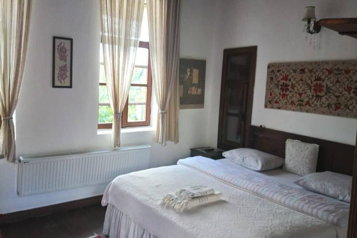 Un dormitorio con una cama grande, techo de madera, radiador y una alfombra roja con estampado.