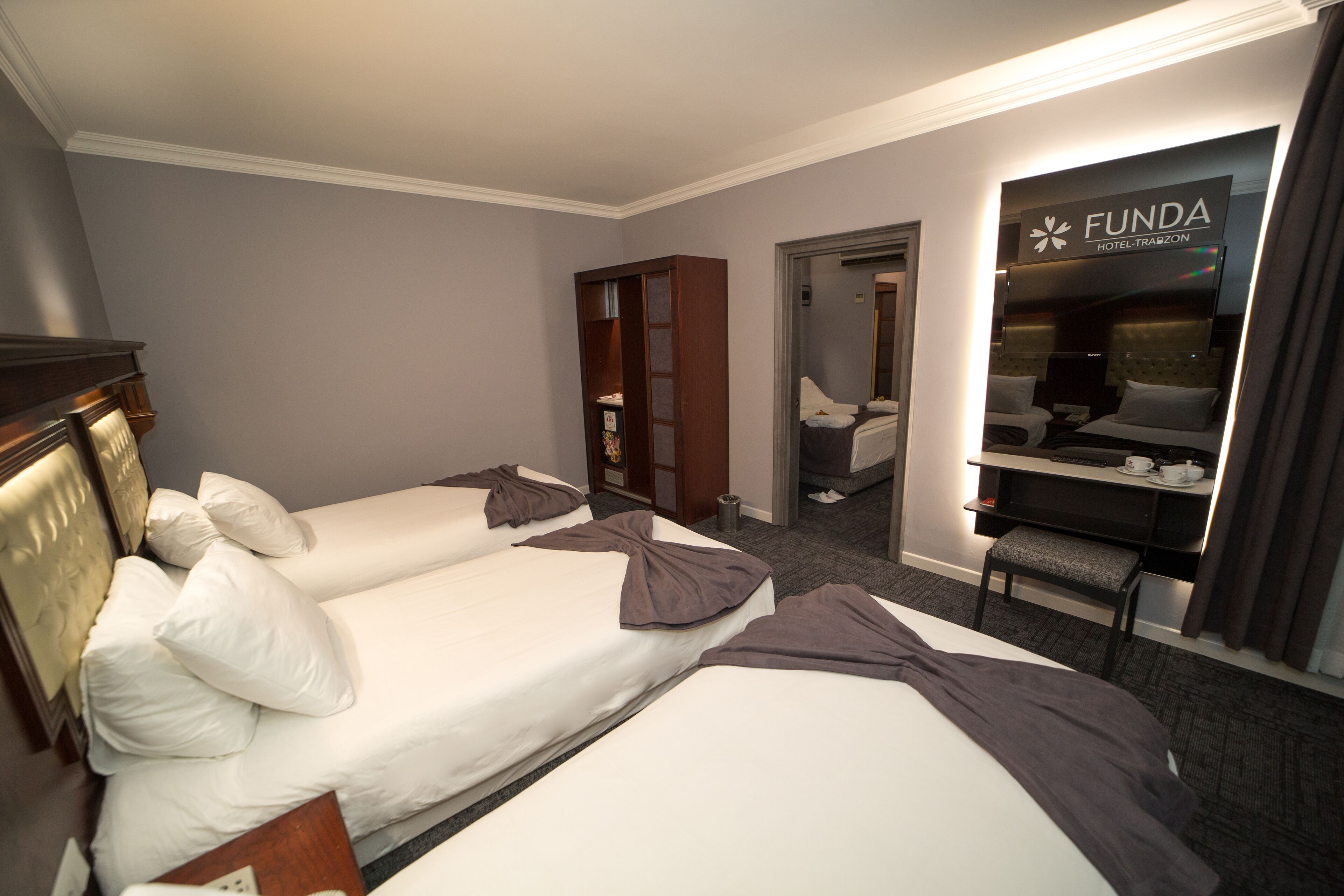 Habitación de hotel con dos camas, un armario, un escritorio y un espejo.