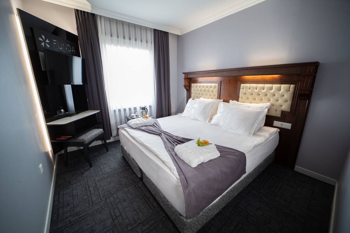 A hotel room with a large bed, a desk, and a television.