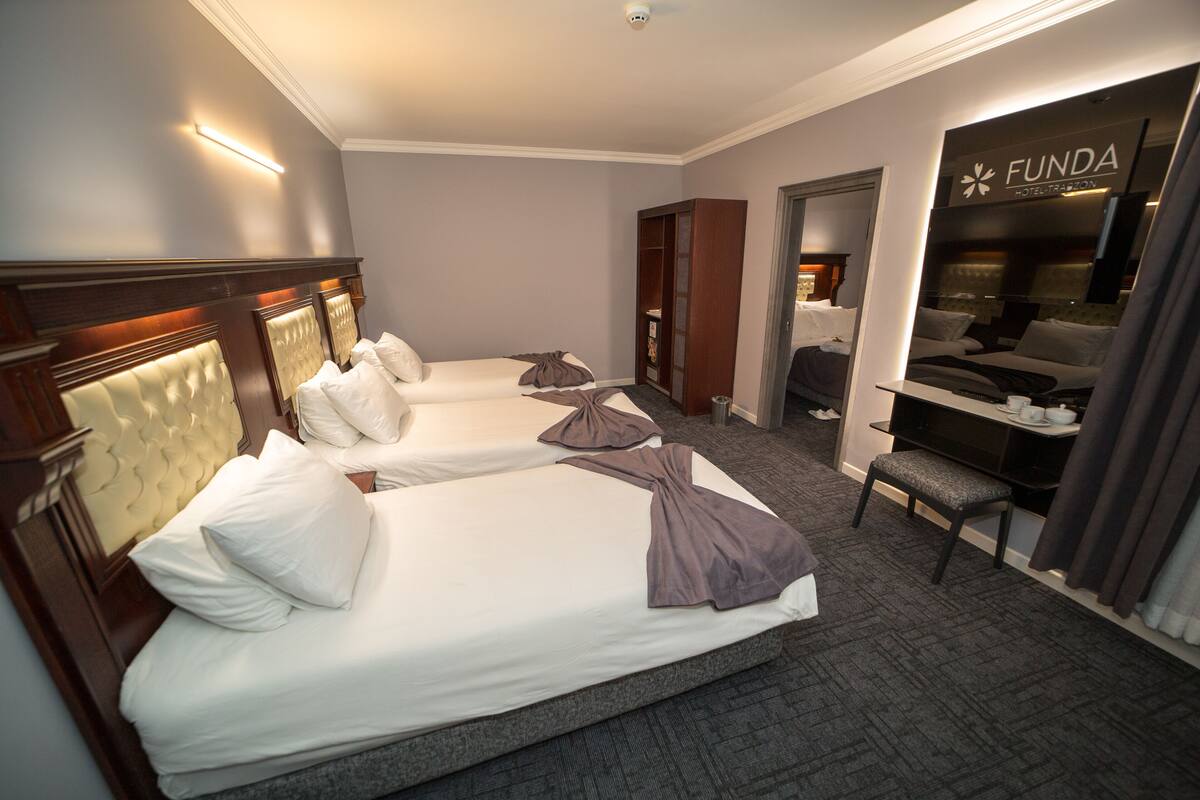A hotel room with two beds, a desk, and a wardrobe.