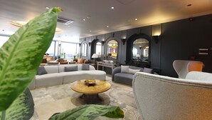 A modern hotel lobby with a sofa set, a round coffee table, and a large plant in the foreground. - Funda Hotel (Trabzon)