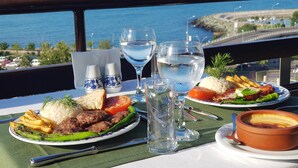 A table set with plates of food, glasses of water, and a bowl of soup, overlooking a coastal view. - Funda Hotel (Trabzon)
