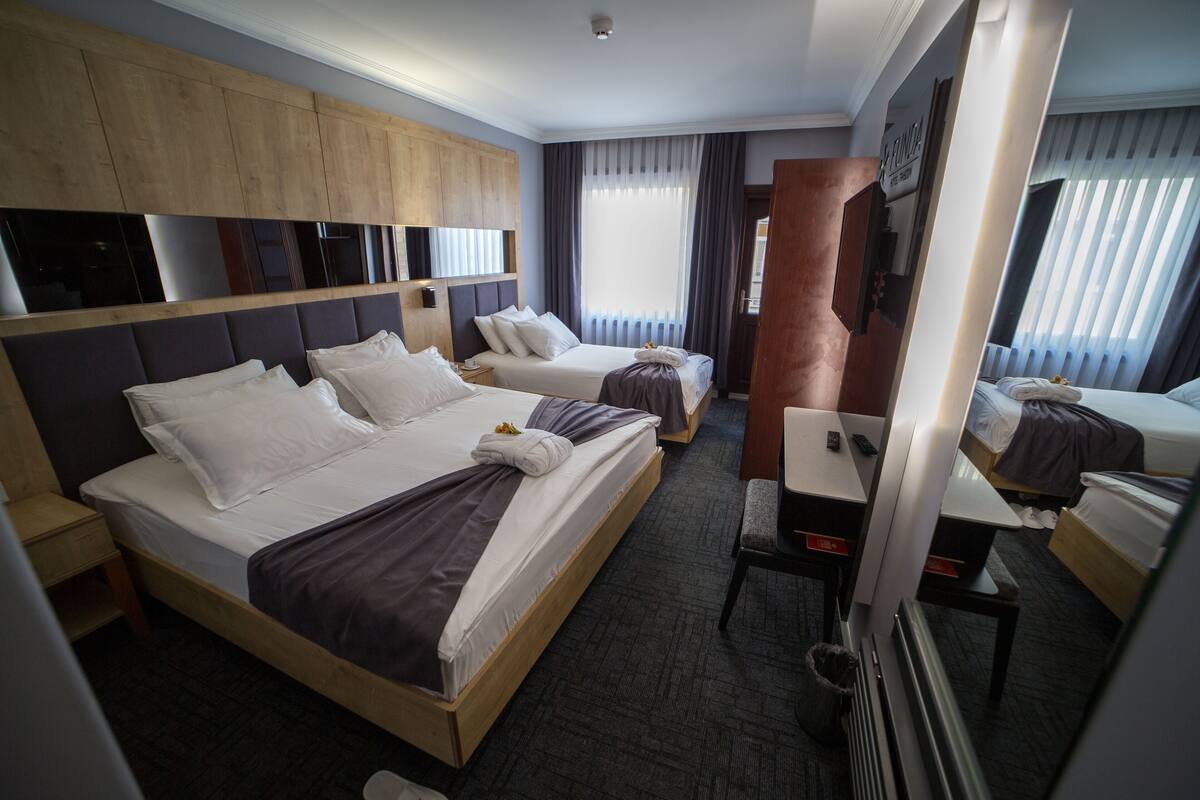 A hotel room with two beds, a desk, and a mirror.