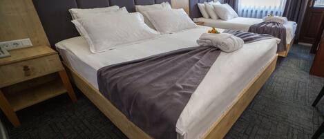 A hotel room with a large bed, a smaller bed, a nightstand, a mirror, and a window with curtains.