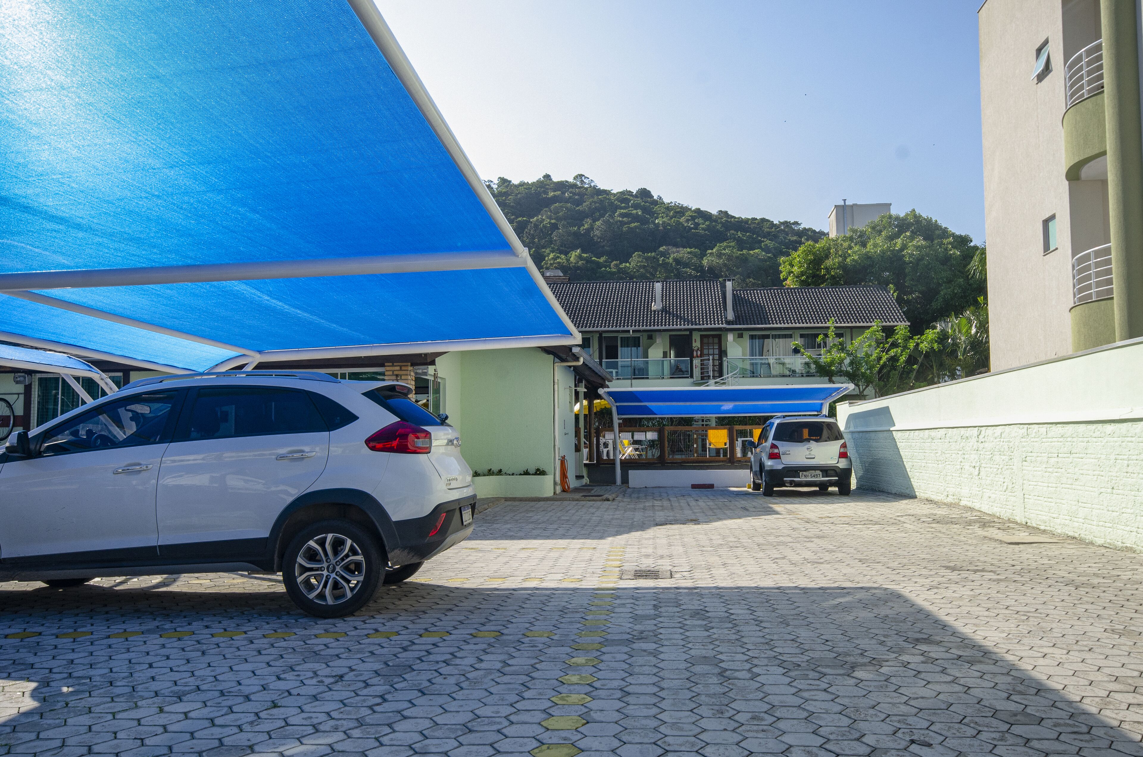 Un estacionamiento con dos coches aparcados bajo una cubierta azul.