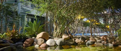 A tranquil garden with a pond, rocks, and lush greenery.