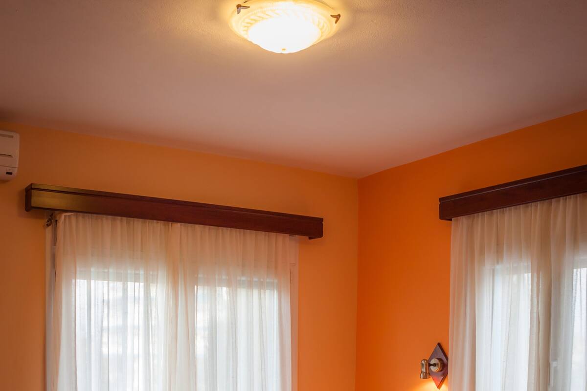 Ein Hotelzimmer mit einem Bett, Vorhängen, einem Nachttisch und einer Wandlampe.