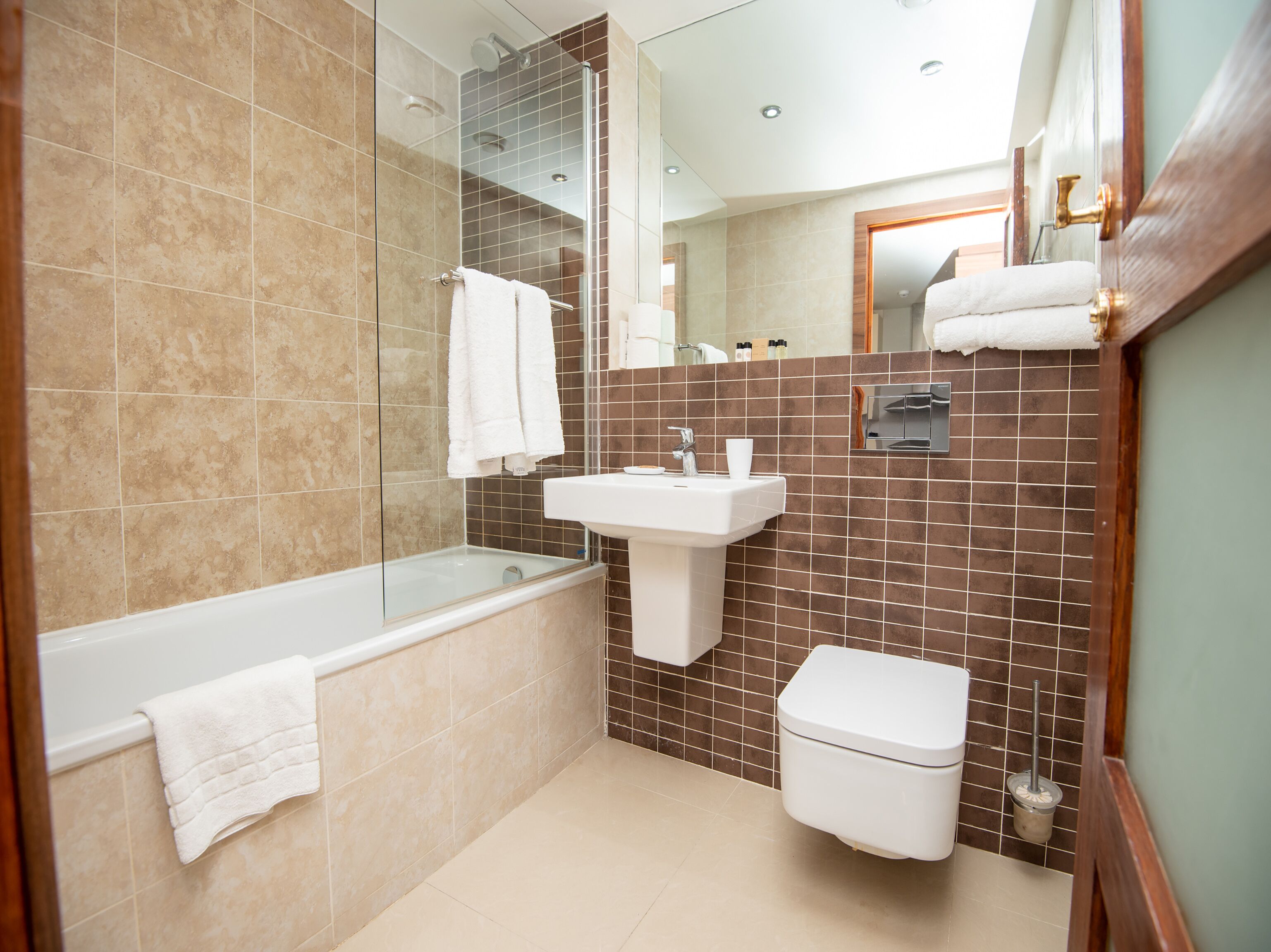 Een moderne badkamer met een douche met glazen wand, een wit wastafelmeubel en een toilet.