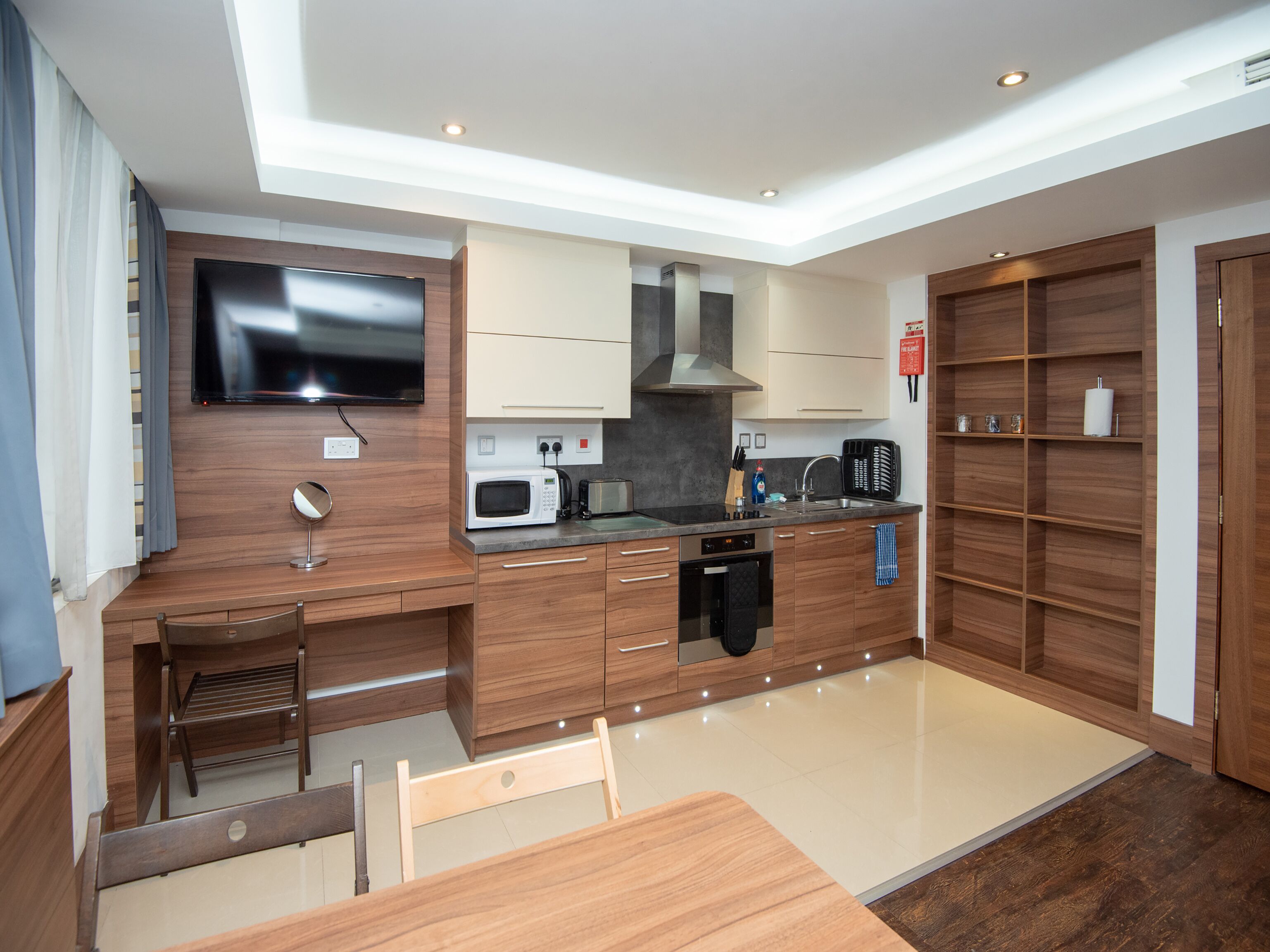 A modern kitchen with wooden cabinets, a built-in microwave, a toaster, and a sink.