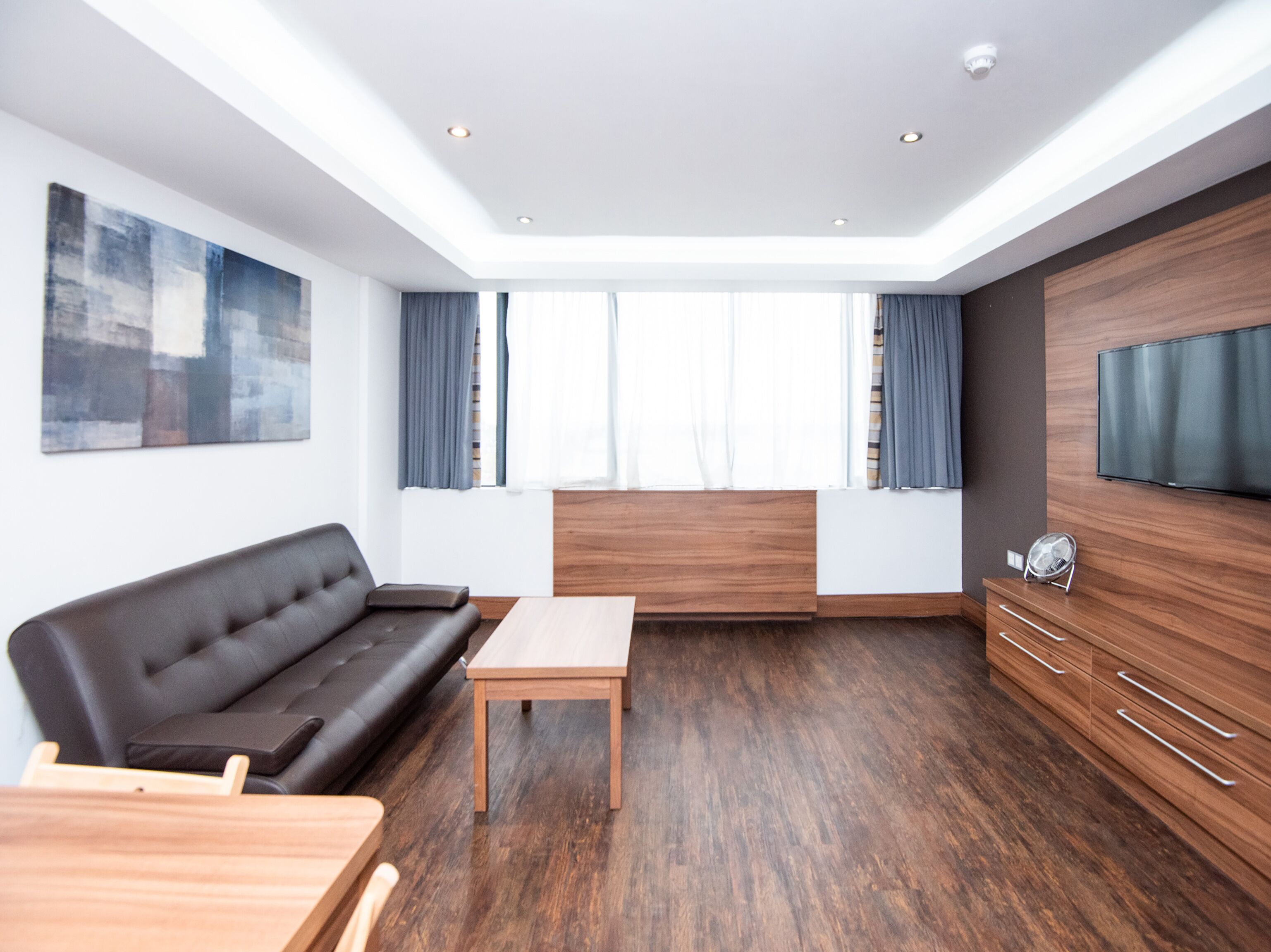 Een moderne woonkamer met een bank, een salontafel, een televisie en een houten kast.