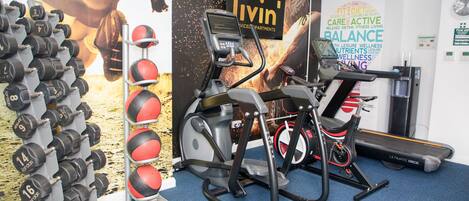 A gym with exercise equipment, a wall with motivational words, and a treadmill.