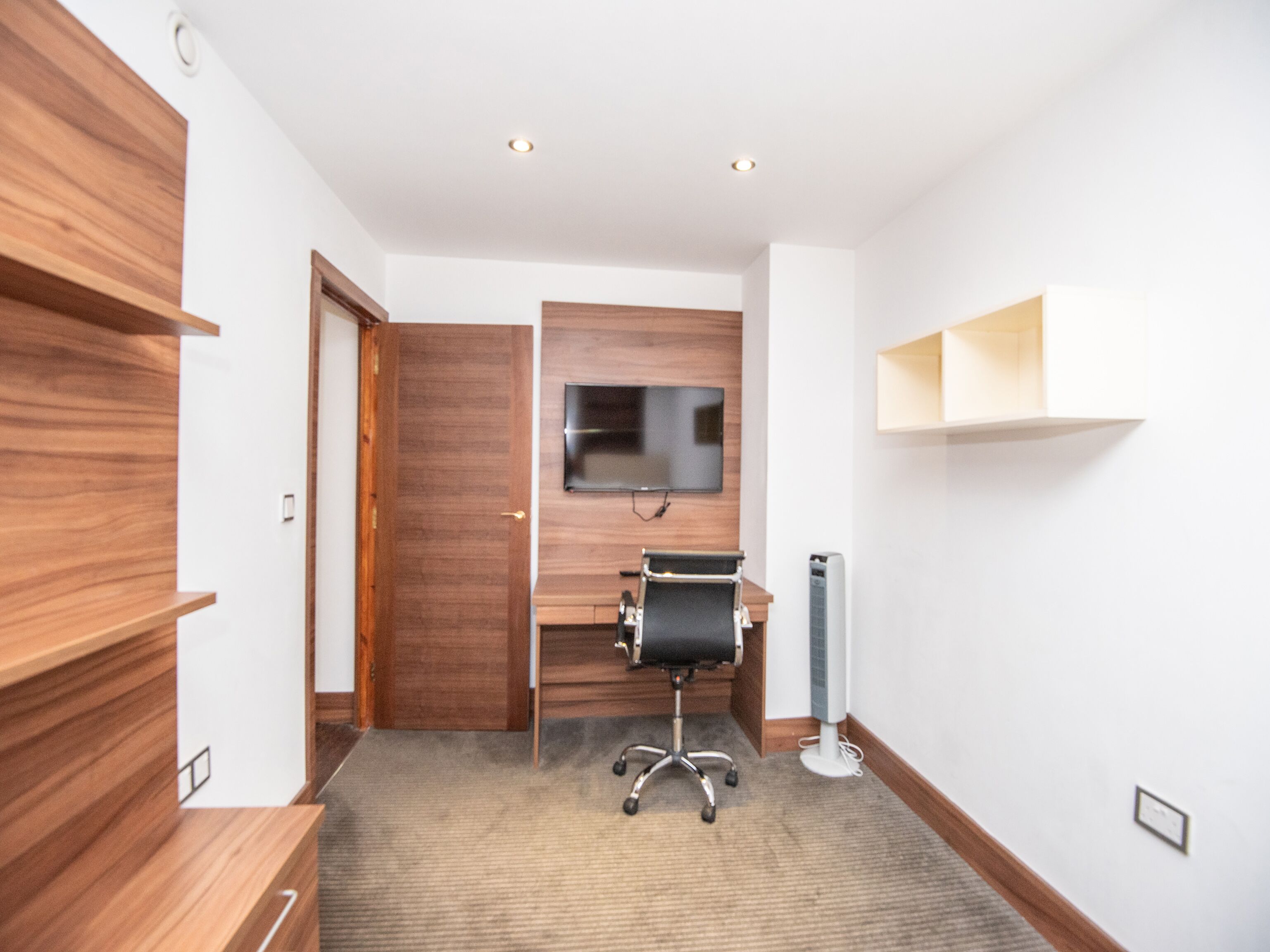 Un espacio de oficina moderno con un escritorio, una silla y un televisor montado.