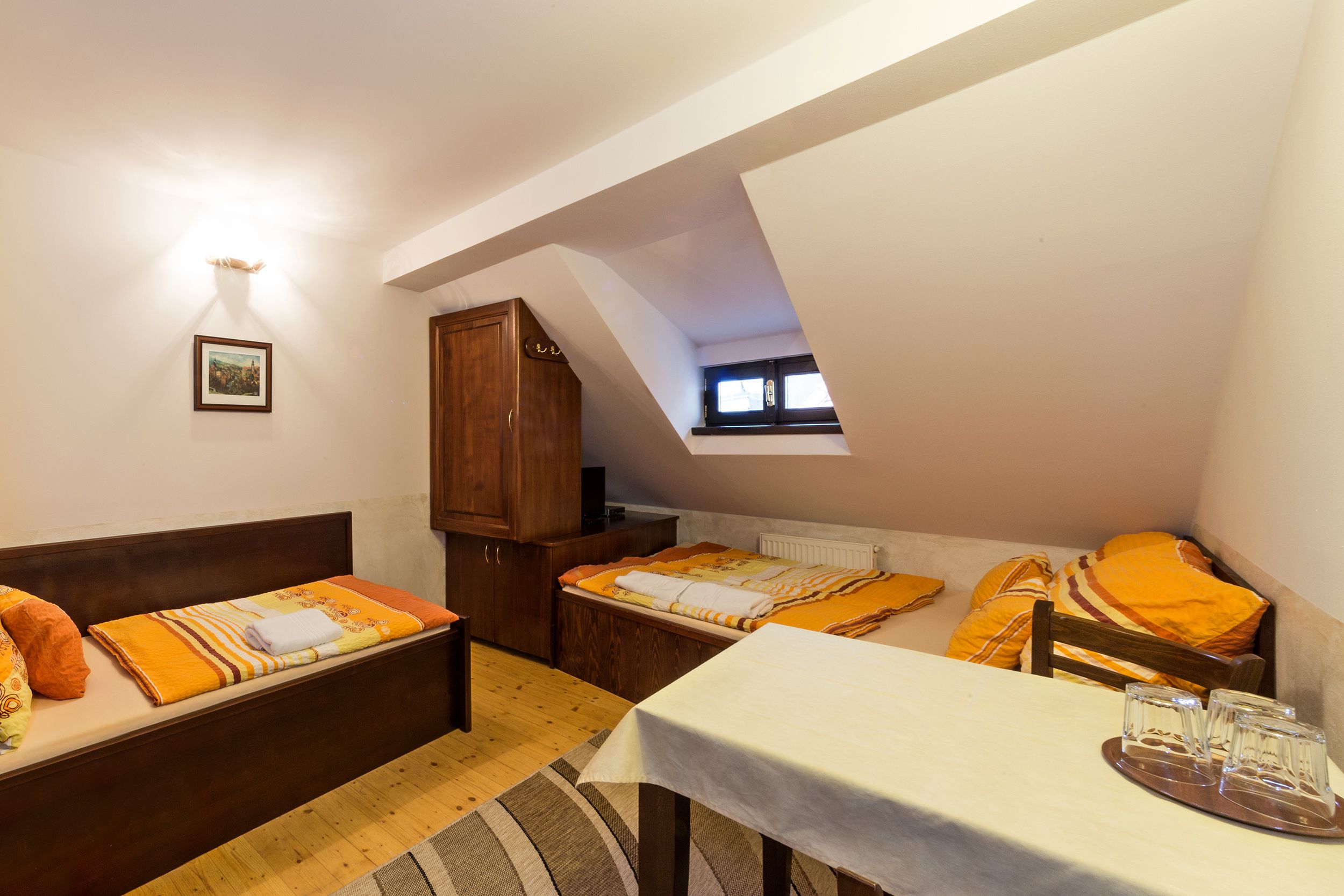 A small, cozy room with two beds, a table, and a window.