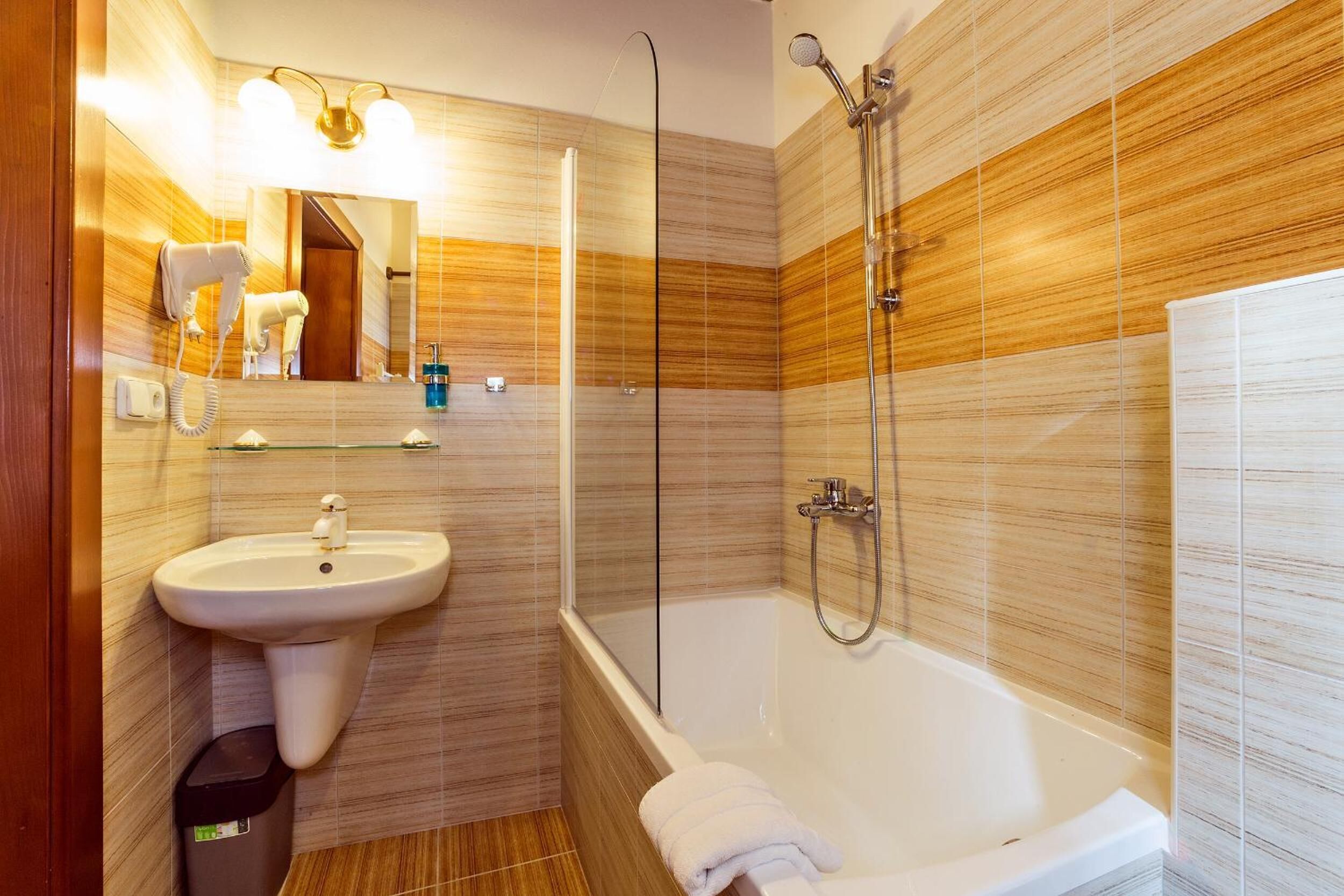 Un baño moderno con lavamanos, espejo y ducha con mampara de vidrio.