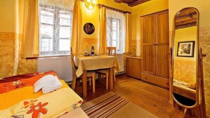 Une chambre confortable avec un lit, une table et une chaise, une armoire en bois et un miroir.
