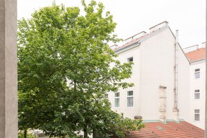 Um edifício com telhado de telhas vermelhas, paredes brancas e uma grande árvore em frente.