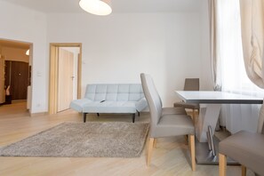 A modern living room with a sofa, dining table, chairs, and a rug.