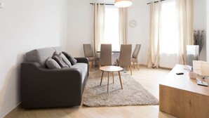 Una sala de estar moderna con un sofá, una mesa redonda de centro y un comedor con sillas.