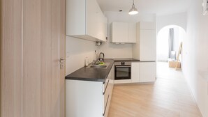 Una cocina moderna con armarios blancos, encimera negra y horno empotrado.