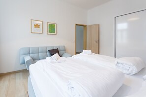 A hotel room with a large bed, a light blue headboard, two framed pictures on the wall, and a wooden wardrobe.