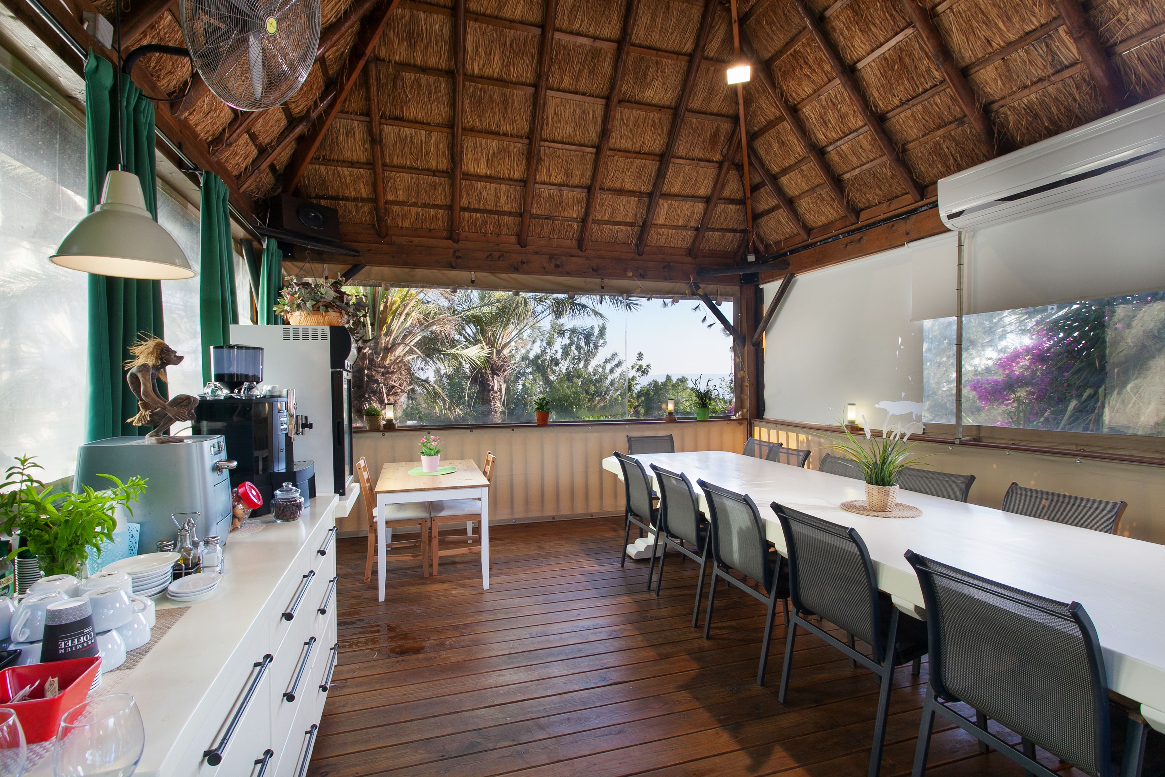 A covered outdoor dining area with a wooden deck, a white table, and chairs.