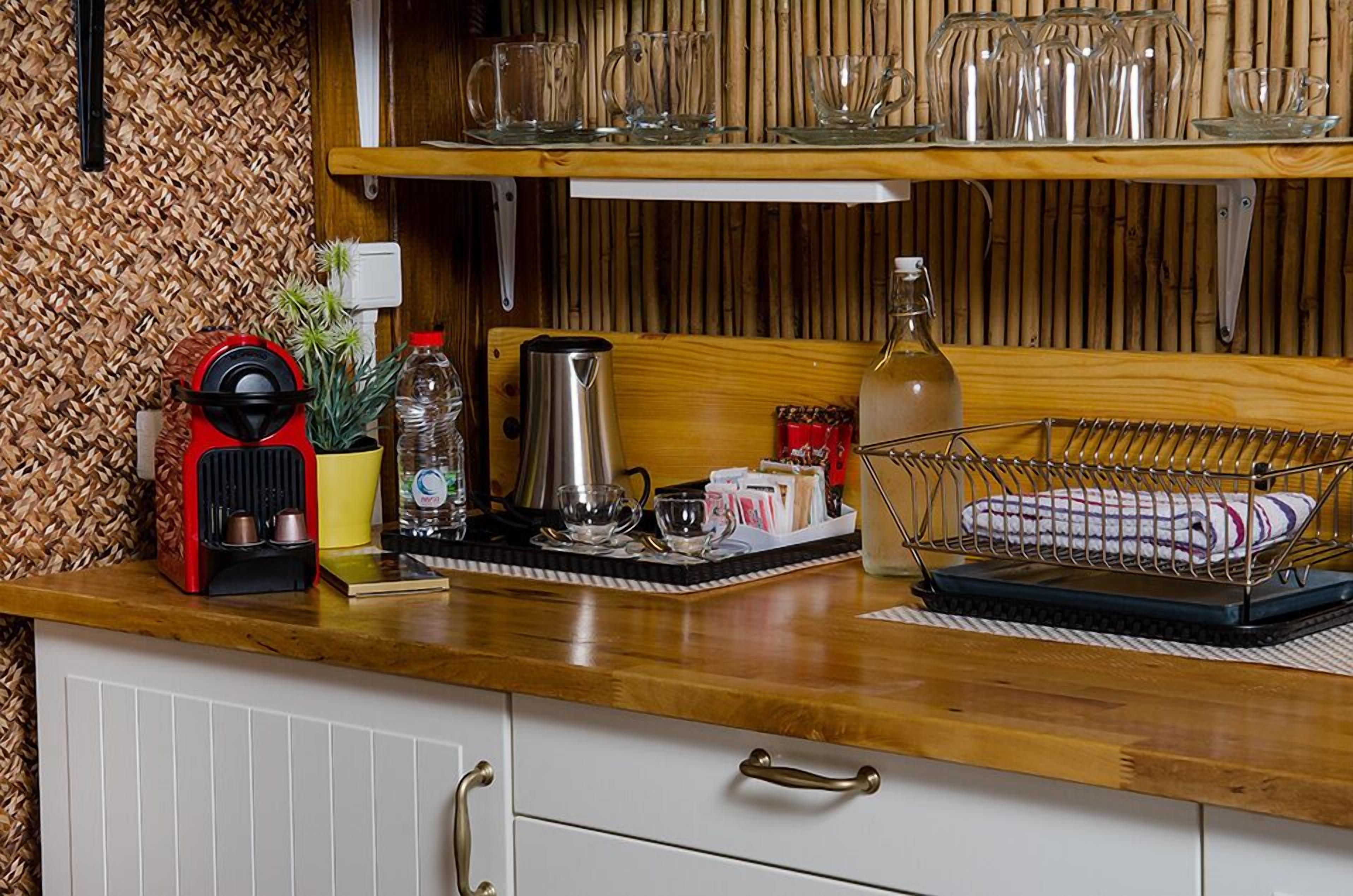 A kitchen counter with a coffee maker, kettle, and various mugs and glasses.