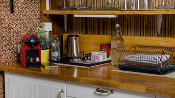 Una encimera de cocina con una cafetera, un hervidor y diferentes tazas y vasos.
