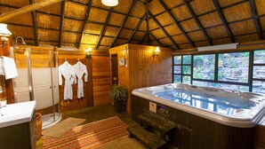 A wooden interior with a hot tub, wooden walls, and a thatched roof. - Out of Africa Sea of Galilee Resort (Had Nes)