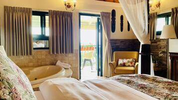 A bedroom with a large bed, a bathtub, and a chair.