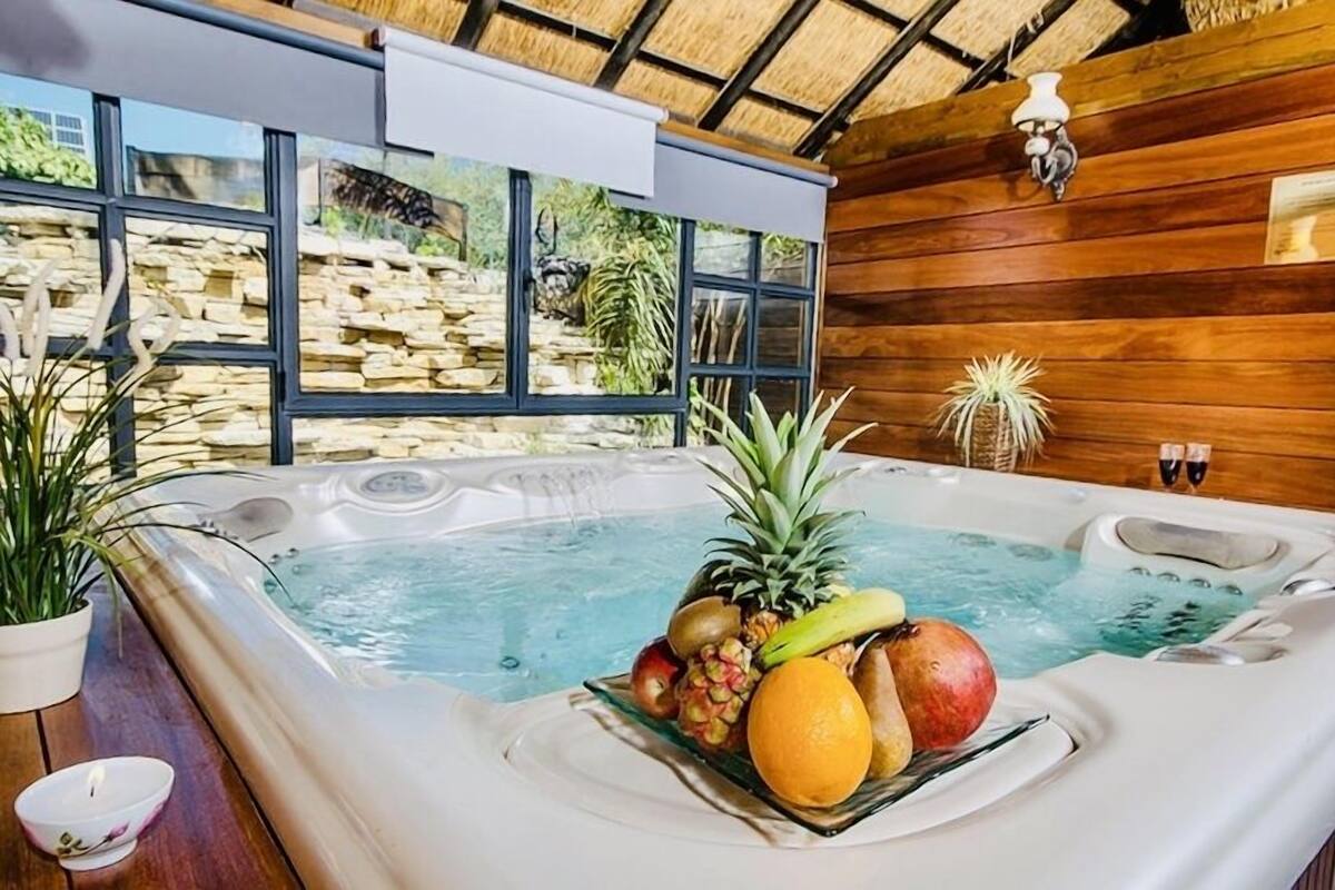 A hot tub with fruit and a stone wall view.