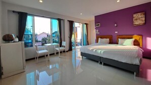A modern hotel room with a large bed, a balcony with a view, and a dining area with a table and chairs. - Graphic House at Chiang Rai (Chiang Rai)