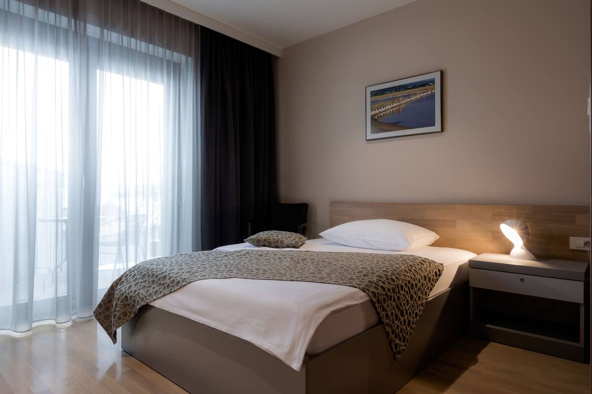 Habitació d'hotel moderna amb un llit, una taula de nit i un calaixer.