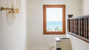 A staircase with a view of the ocean through a window, a wooden floor, and a wall-mounted light fixture. - BYPILLOW California (Málaga)