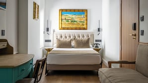 A bedroom with a tufted headboard, a large painting on the wall, bedside lamps, a wooden dresser, and a chair. - BYPILLOW California (Málaga)