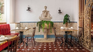 A dining area with a stone fountain, tiled walls, and a red booth. - BYPILLOW California (Málaga)