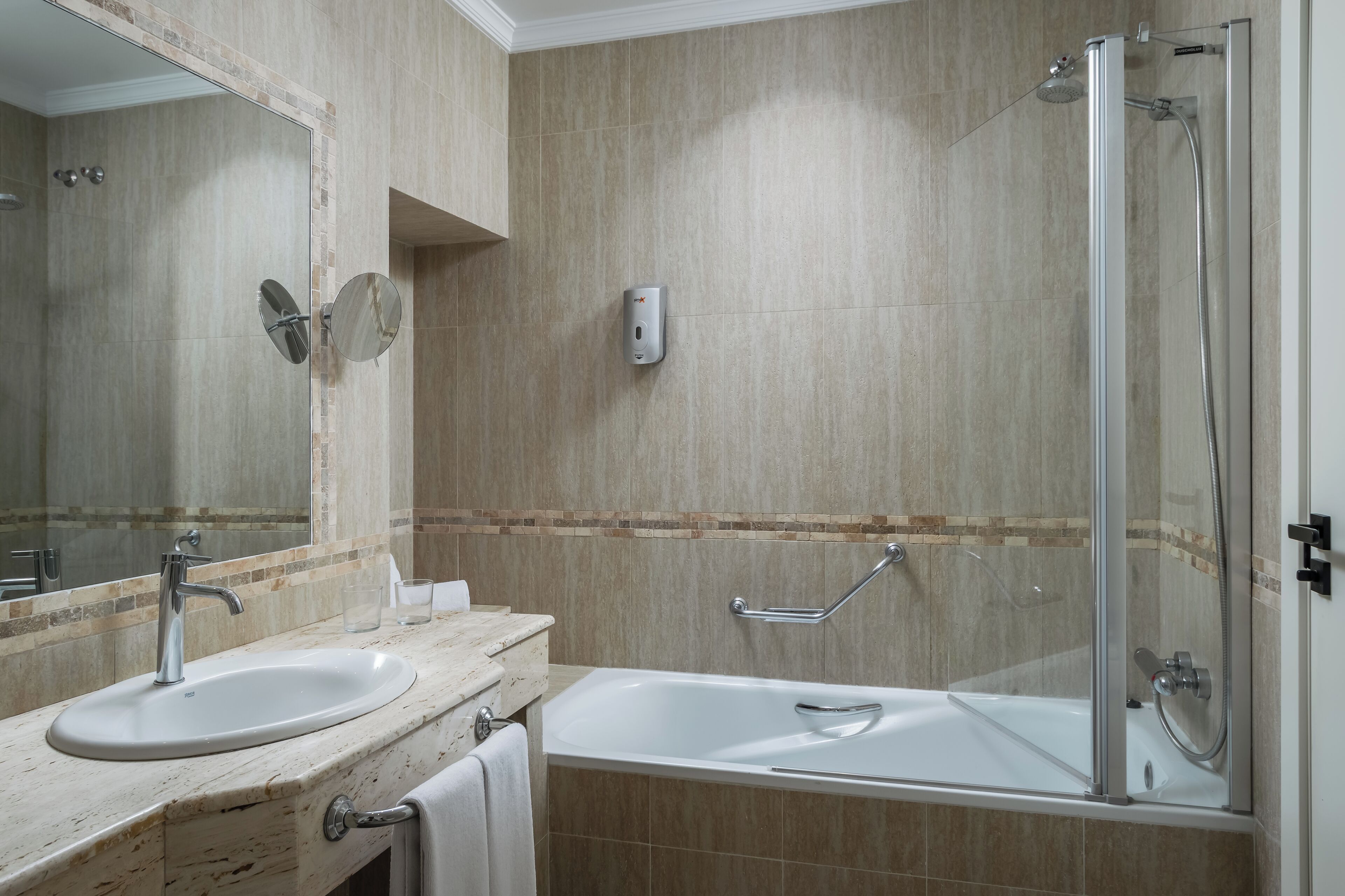 A bathroom with a sink, mirror, and shower area.