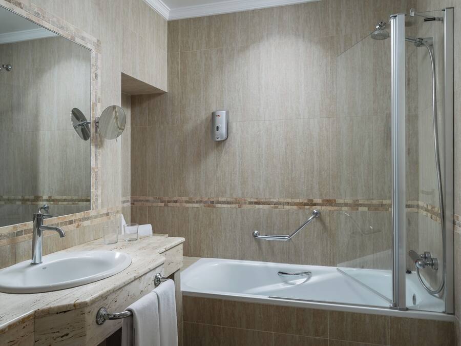 A bathroom with a sink, mirror, and shower area.