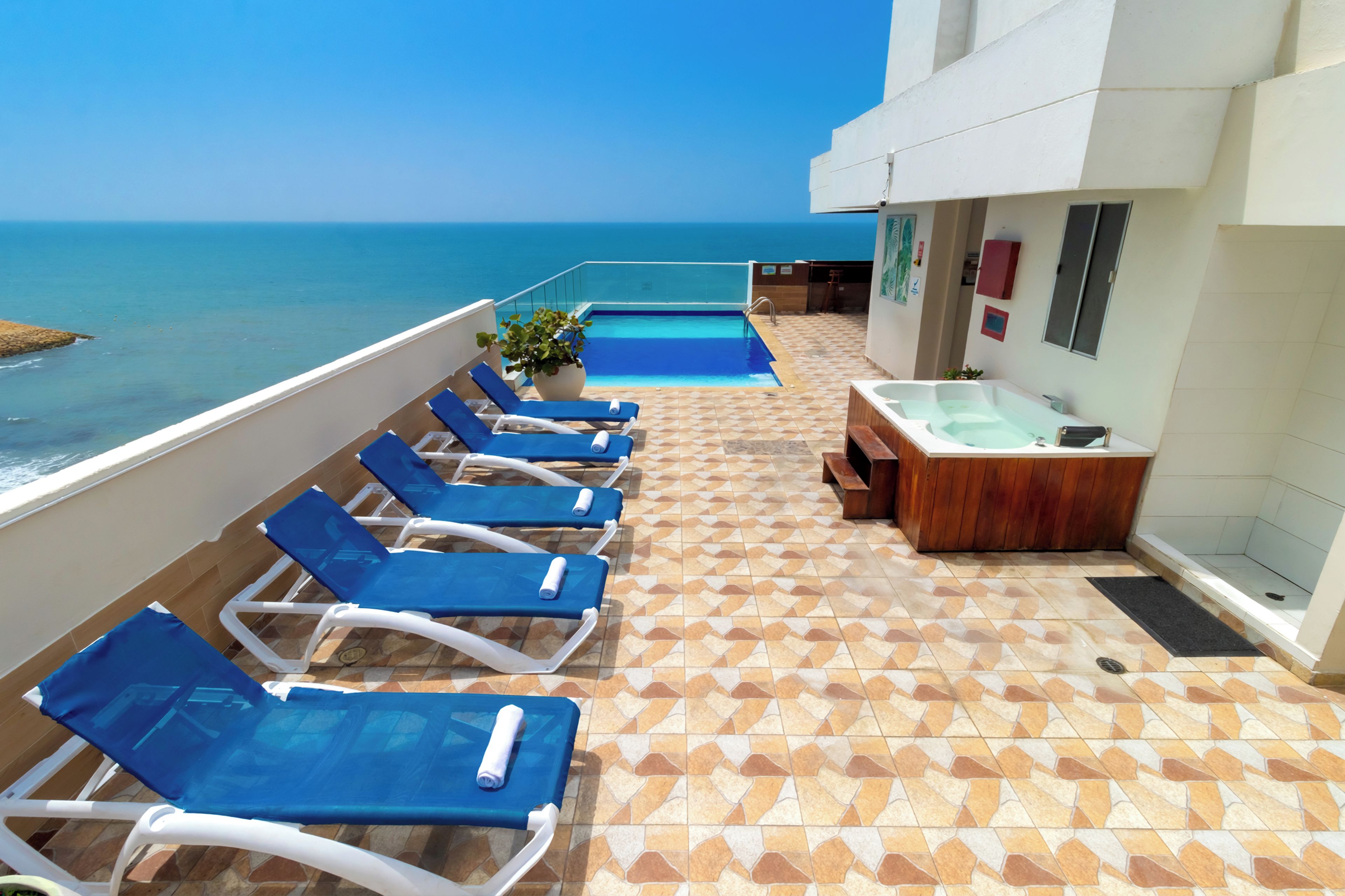 A poolside area with lounge chairs and a hot tub.
