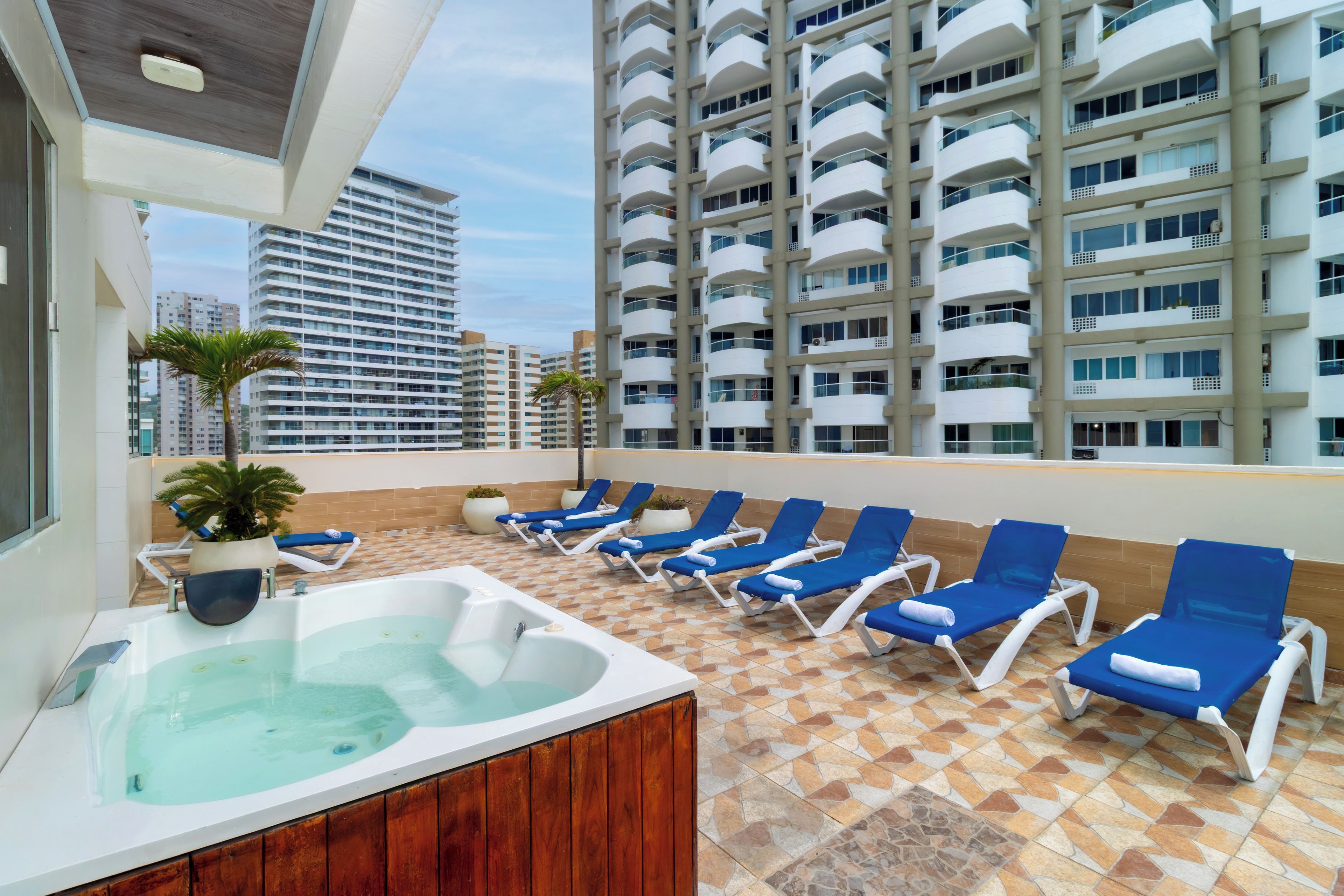 A rooftop terrace with a hot tub and lounge chairs.