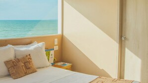 A bedroom with a bed, pillows, a nightstand, a book, and a view of the ocean. - Hotel Aixo Suites By Geh Suites (Cartagena)