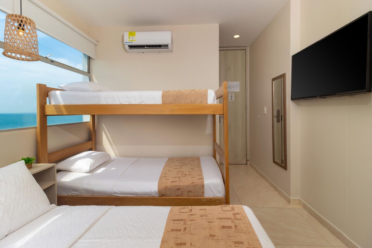 A bunk bed room with a television on the wall, a window with a view, and an air conditioning unit.