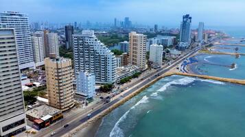 A coastal cityscape with high-rise buildings, a beach, and a road running parallel to the waterfront.
