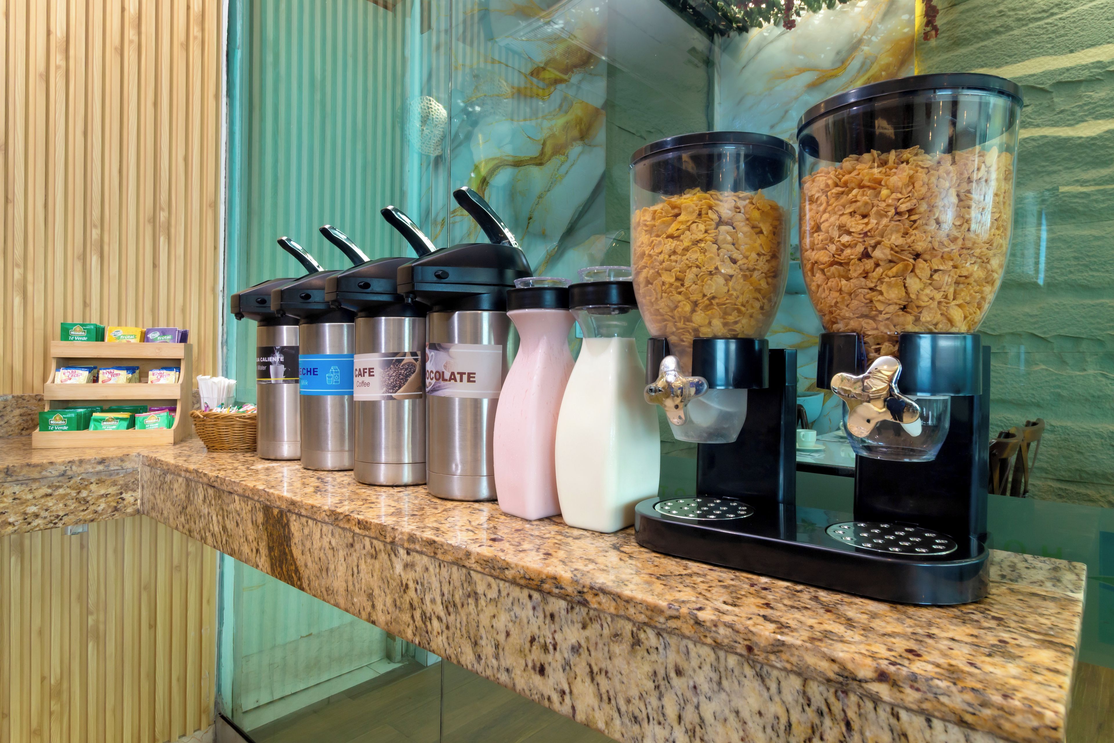 A breakfast bar with coffee, milk, and cereal dispensers.