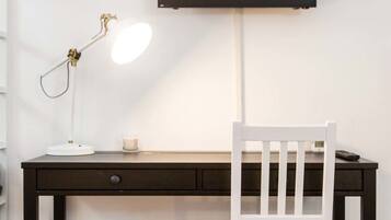 Een bureau met een televisie, een lamp en een prullenbak.
